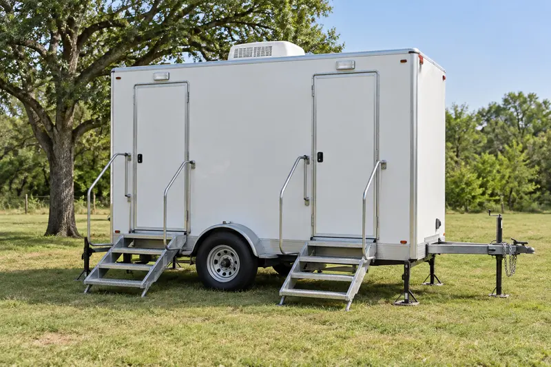 White portable restroom trailer with access steps and handrails